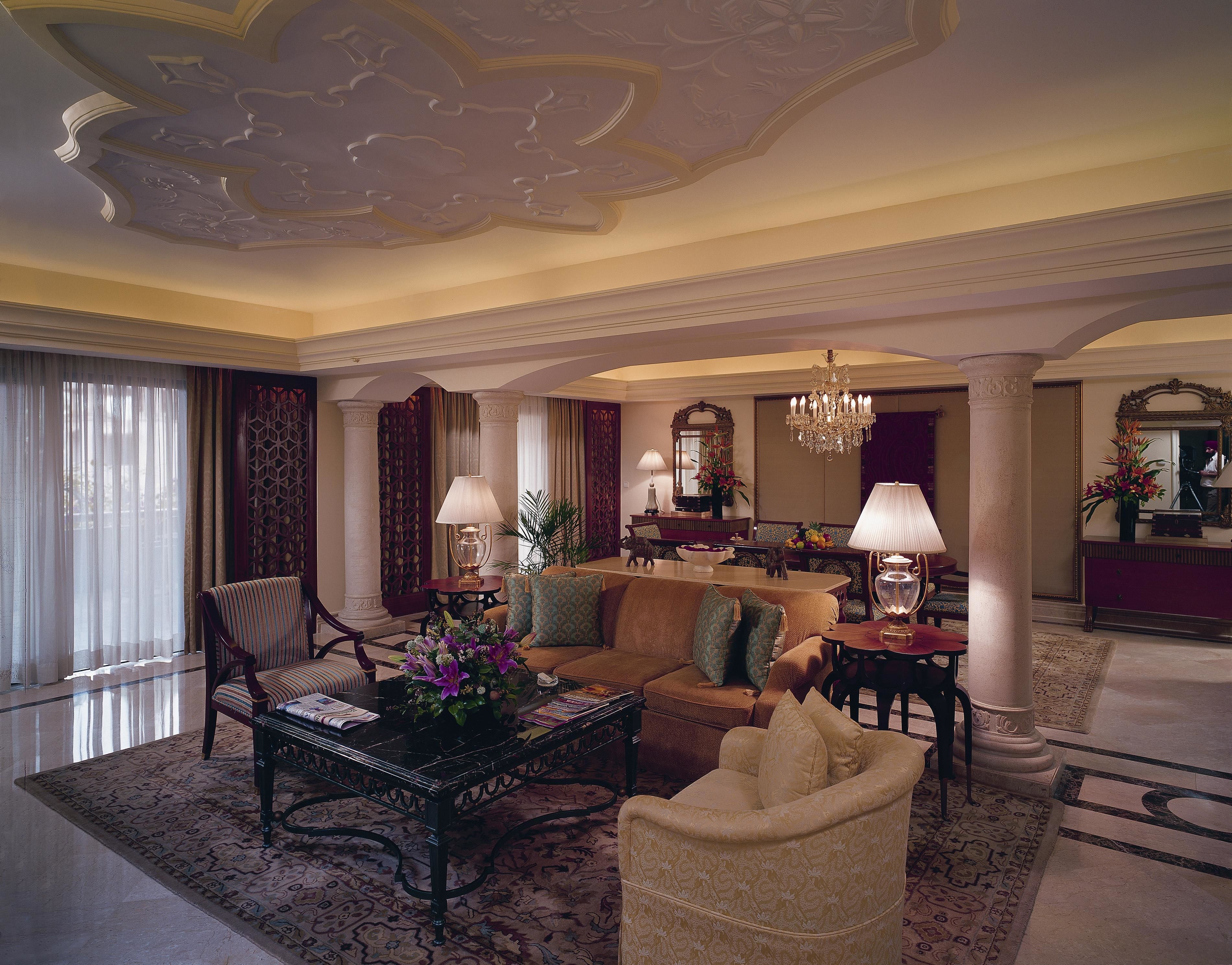 A spacious living room with a sofa, armchairs, a coffee table, and a chandelier.