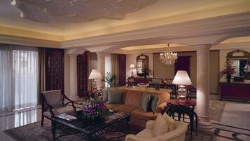 A spacious living room with a sofa, armchairs, a coffee table, and a chandelier.