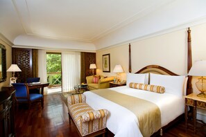 Relax in this inviting room with a large bed, sofa, and armchairs, perfect for unwinding with a view of the surrounding greenery.