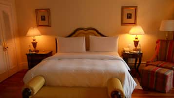 Ein Hotelzimmer mit einem großen Bett, zwei Nachttischen mit Lampen, einem Sessel und zwei gerahmten Bildern an der Wand.