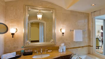 A luxurious bathroom with a large mirror, ornate vanity, and a bathtub.