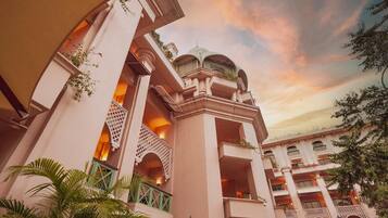 A hotel with multiple balconies, a central dome structure, and lush greenery.