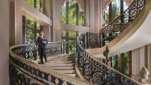 A grand staircase with ornate black railings and a chandelier.