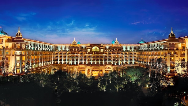 A large, ornate hotel with multiple domes and a symmetrical facade, featuring a central courtyard and lush greenery.