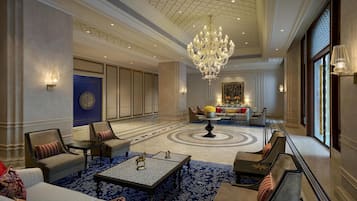 Een ruime lobby met een imposante kroonluchter, zitgedeeltes en een decoratief vloerkleed.