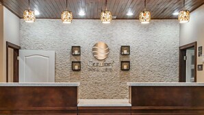 A reception area with a stone wall, a logo, and three pendant lights. - Comfort Inn & Suites Pharr - McAllen (Pharr)