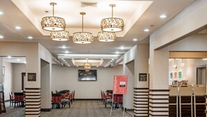 A hotel lobby with a patterned carpet, multiple dining tables, chairs, and a reception desk. - Comfort Inn & Suites Pharr - McAllen (Pharr)