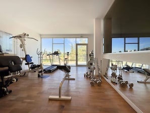 A gym with cardio machines, weightlifting equipment, and large windows offering a view of the outdoors. - The Classic Hotel Nicosia - Handwritten Collection (Nicosia)