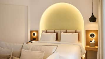 Una habitación de hotel moderna con una cama grande, dos mesitas de noche, un escritorio y una lámpara colgante.