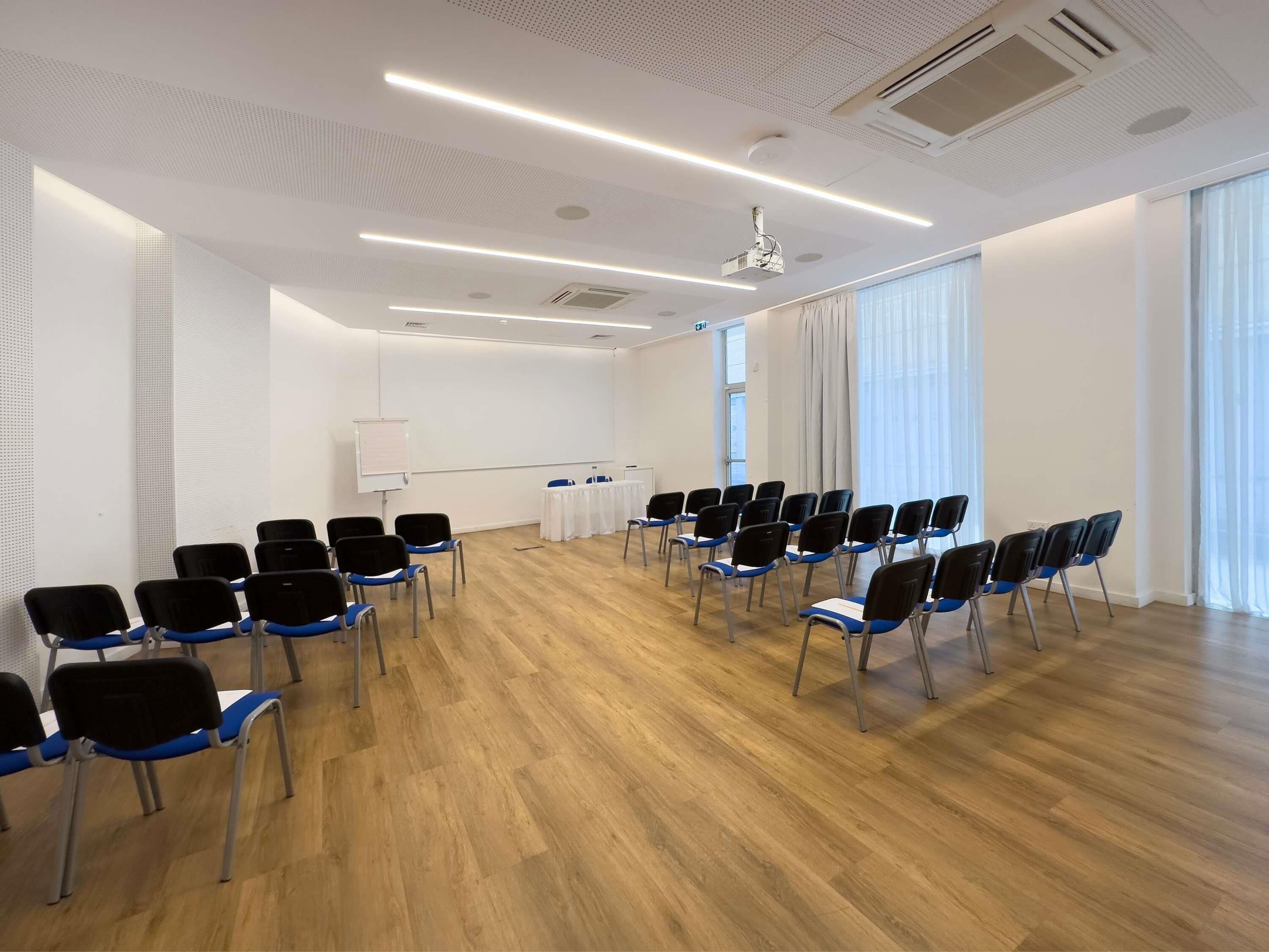 A conference room with rows of chairs, a whiteboard, and a projector.