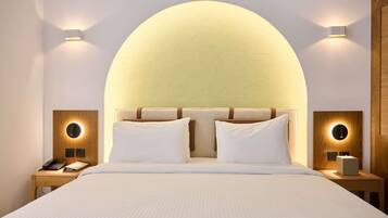 A modern hotel room with a large bed, two bedside tables, and wall-mounted lighting.