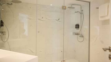 A modern glass-enclosed shower with a handheld showerhead and a wall-mounted faucet.