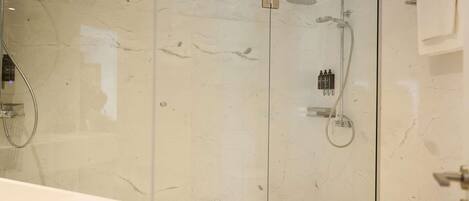 A modern glass-enclosed shower with a handheld showerhead and a wall-mounted faucet.