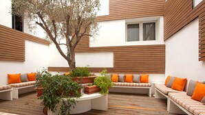 Un espace extérieur moderne, aménagé avec des lattes de bois, des bancs rembourrés et des plantes en pot.