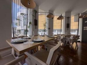 A dining area with tables set for service, large windows with vertical blinds, and hanging pendant lights. - The Classic Hotel Nicosia - Handwritten Collection (Nicosia)