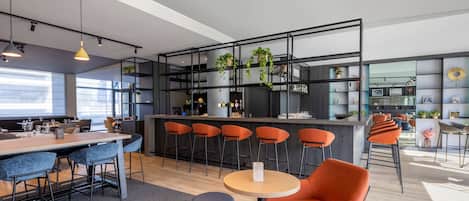 A modern kitchen with bar stools, a round table, and a seating area with chairs.