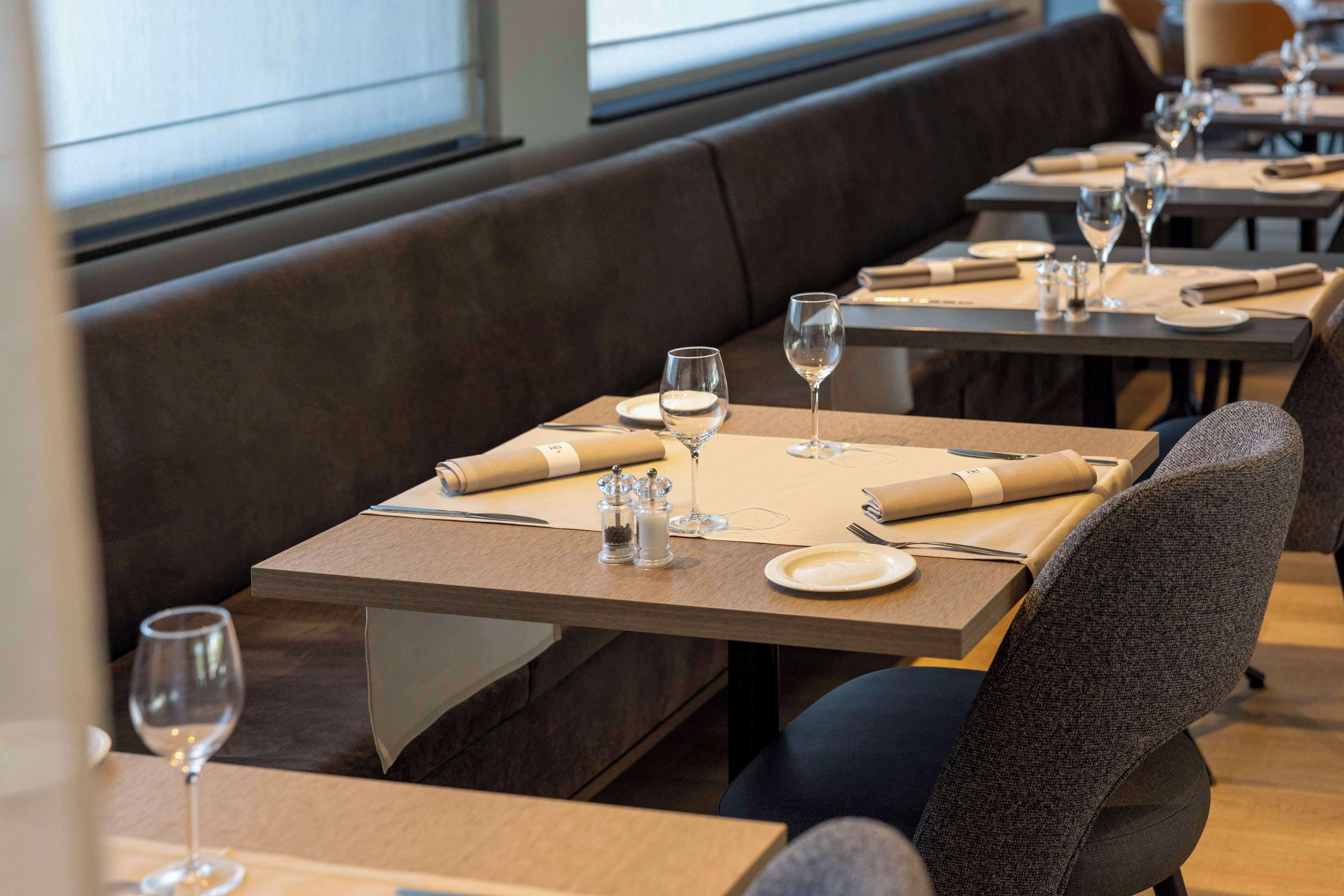 A restaurant with tables set for dining, including plates, cutlery, and glasses.