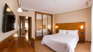 A hotel room with a large bed, bedside lamps, a flat-screen TV, and a wooden headboard. - NH San Pedro (Marbella)