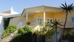 A yellow building with a white staircase leading to a covered porch. - Hotel Quinta das Pratas (Cartaxo)