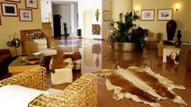 A lobby with a polished floor, wicker furniture, and framed pictures on the walls. - Hotel Quinta das Pratas (Cartaxo)