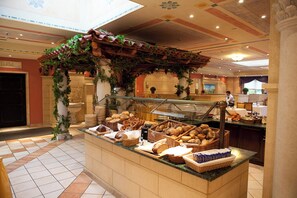 A breakfast buffet area with various breads and pastries displayed on a counter. - Dorint Marc Aurel Resort Bad Goegging (Neustadt an der Donau)