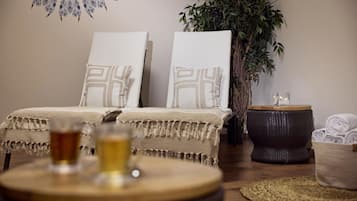 A cozy bedroom with two beds, a large plant, a small side table, and a woven basket.