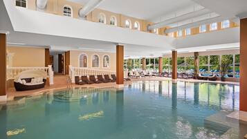A large indoor swimming pool with lounge chairs and a covered seating area.
