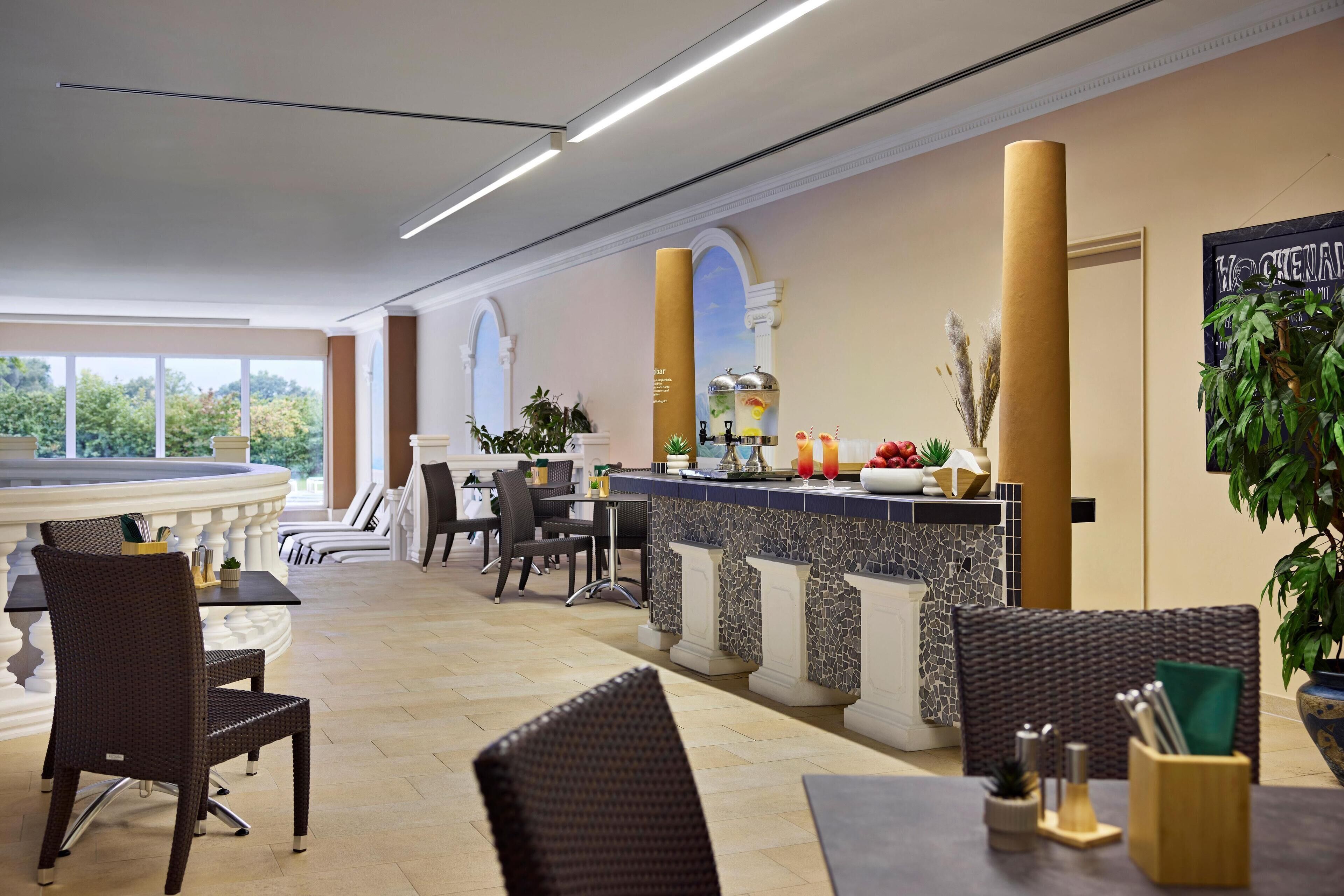 Un vestíbulo de hotel con una zona de bar, arreglos de asientos y vistas al exterior.