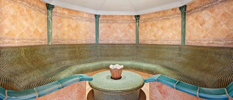 A spa room with a curved seating area, a central decorative urn, and a tiled floor.