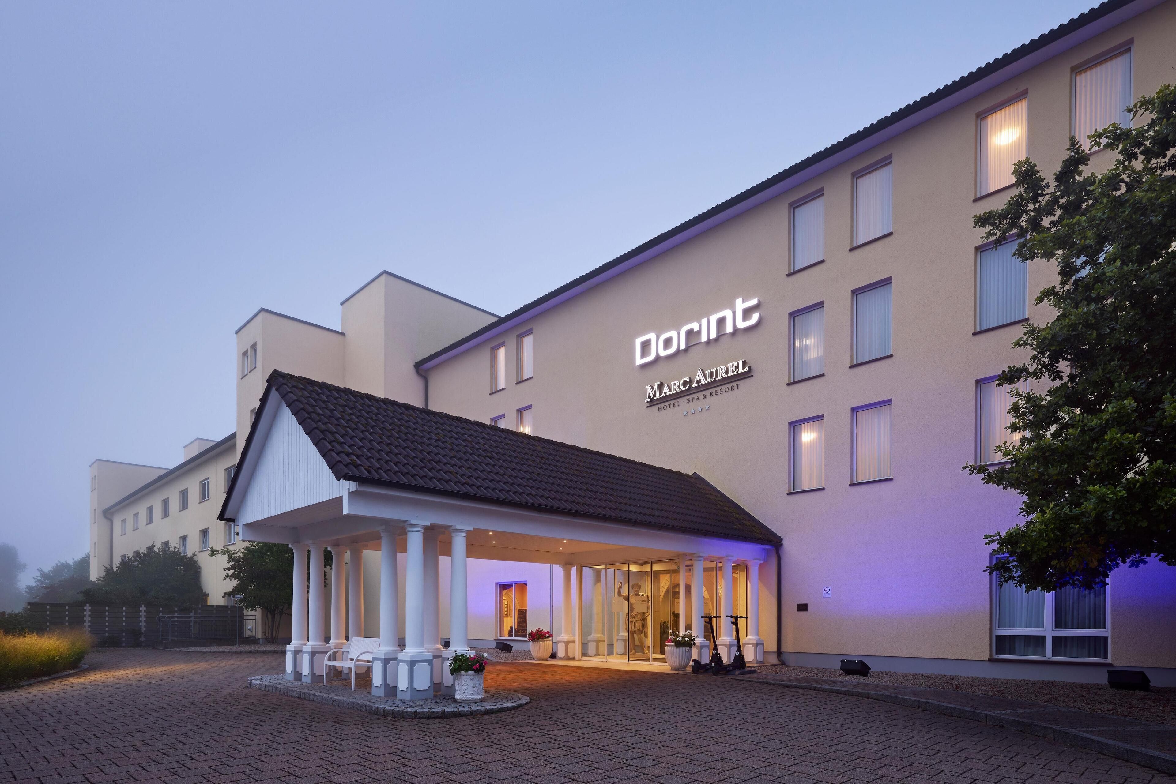 Un hotel con entrada cubierta, asientos al aire libre y un letrero que indica Hotel & Spa Marc Aurel.