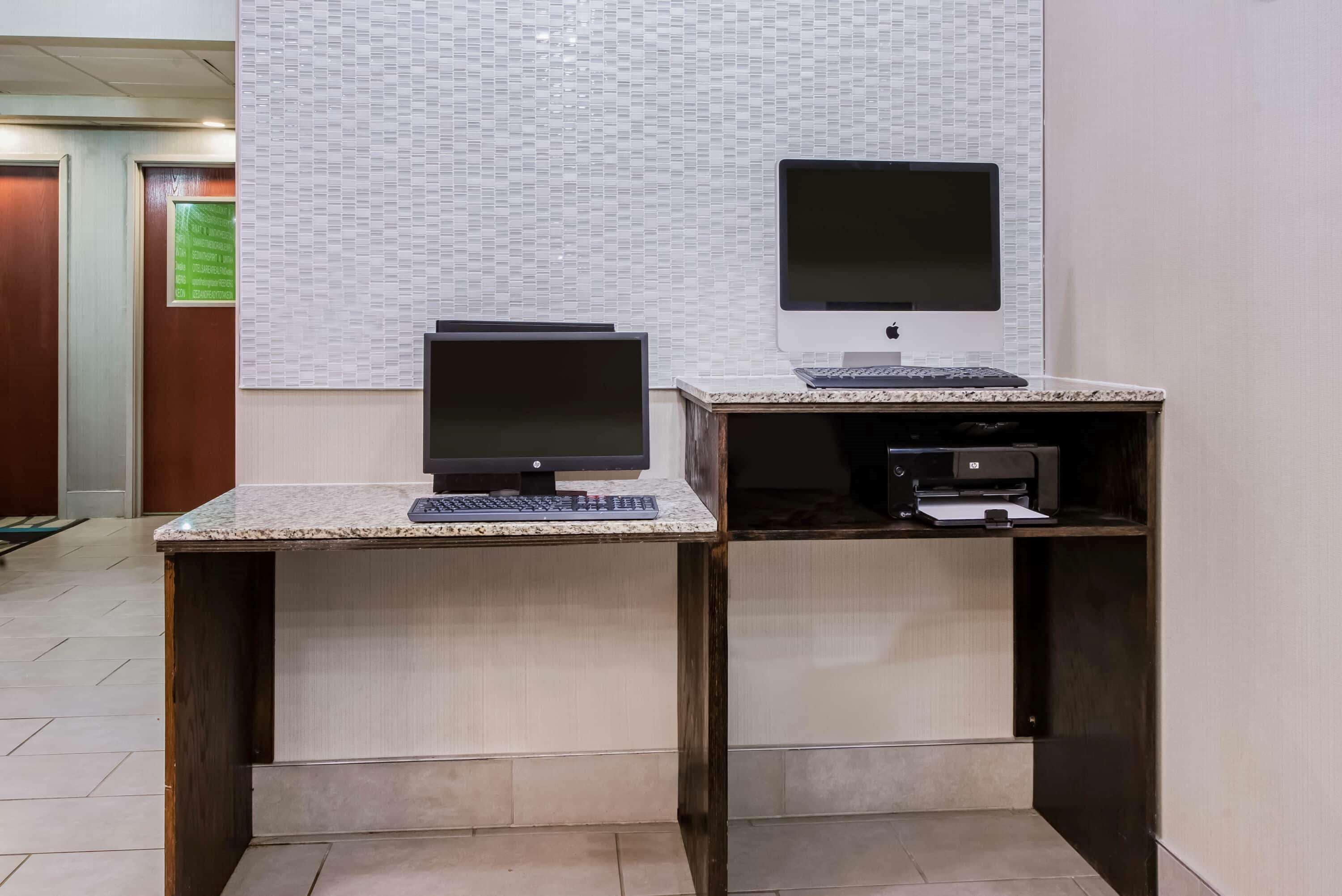 Un bureau avec deux écrans, un clavier et une imprimante, situé dans le hall d’un hôtel.