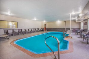 Una piscina con solárium empedrado, sillas de descanso y vestuarios.