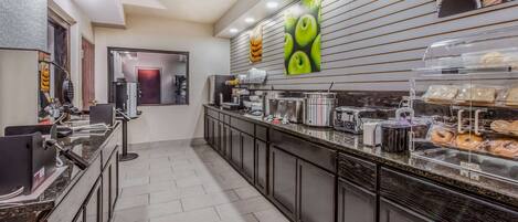 A modern kitchen with a long counter, equipped with various appliances and a coffee station.