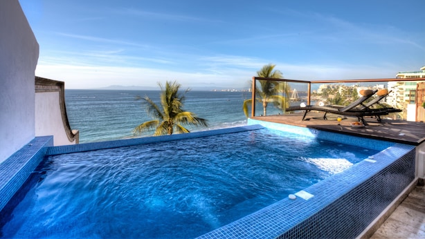 A pool with a view of the ocean, lounge chairs, and palm trees. - Vallarta Shores Beach Hotel (Puerto Vallarta)