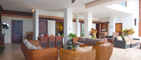 A spacious lobby with wicker furniture, a ceiling fan, and a large window providing natural light.