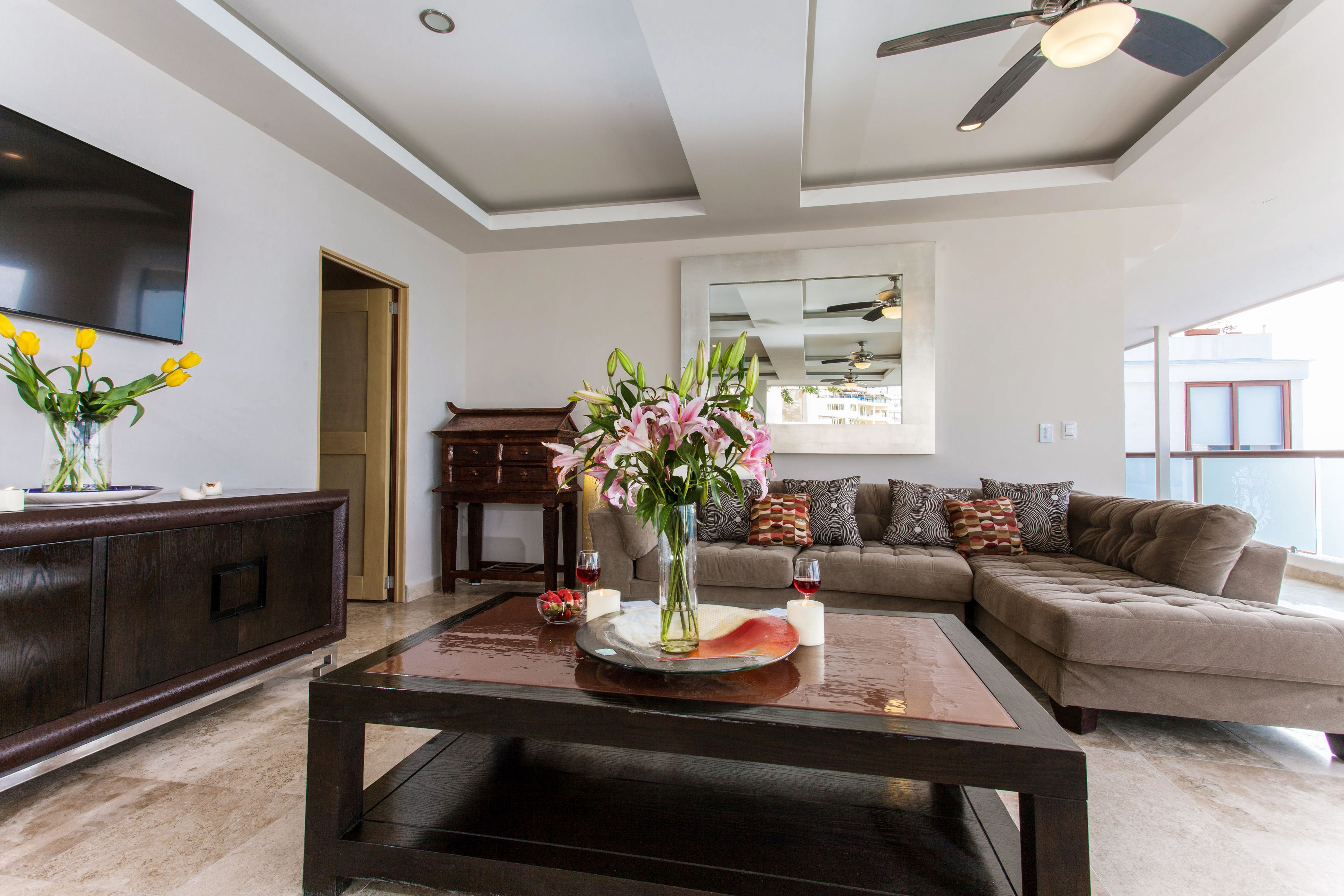A modern living room with a dark coffee table, a sofa, and a TV mounted on the wall.