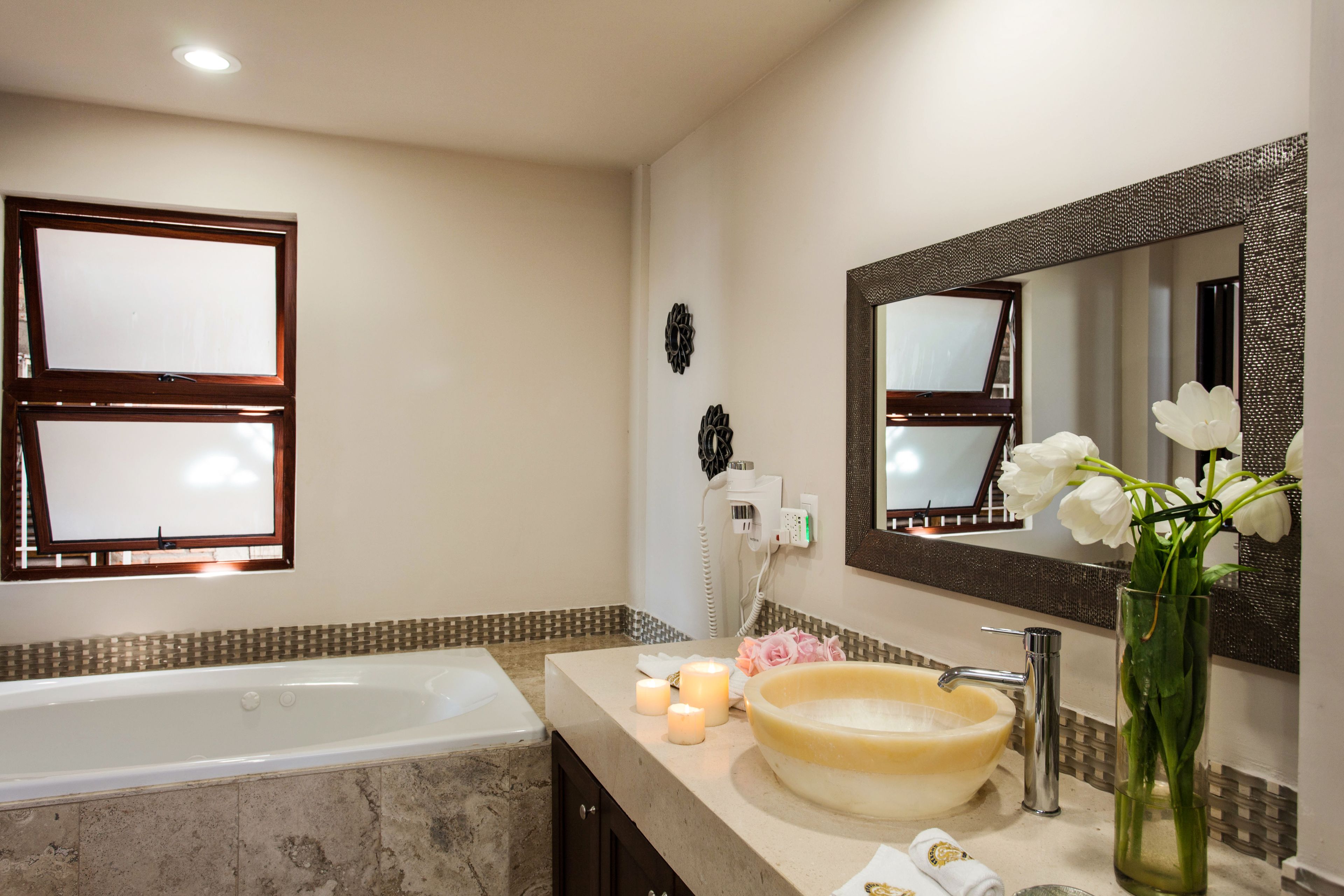 Une salle de bain avec une baignoire, un lavabo avec un grand miroir et des bougies décoratives.
