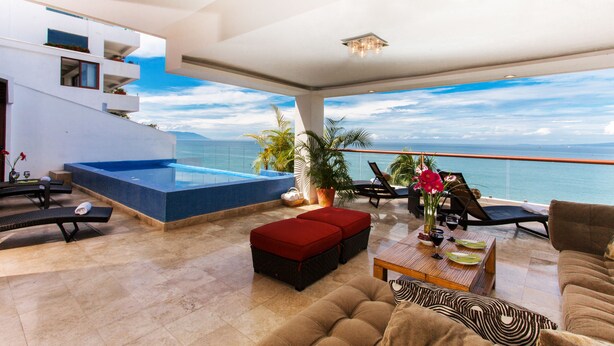 Un espace de vie moderne avec piscine, coin salon extérieur et vue sur la mer.