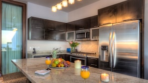 A modern kitchen with stainless steel appliances, a marble countertop, and a breakfast bar. - Vallarta Shores Beach Hotel (Puerto Vallarta)