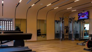 A gym with treadmills, weight machines, and a TV screen.
