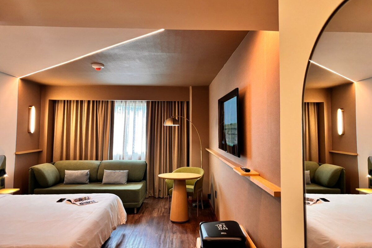 Une chambre d’hôtel avec un lit, un canapé, une petite table et une chaise.