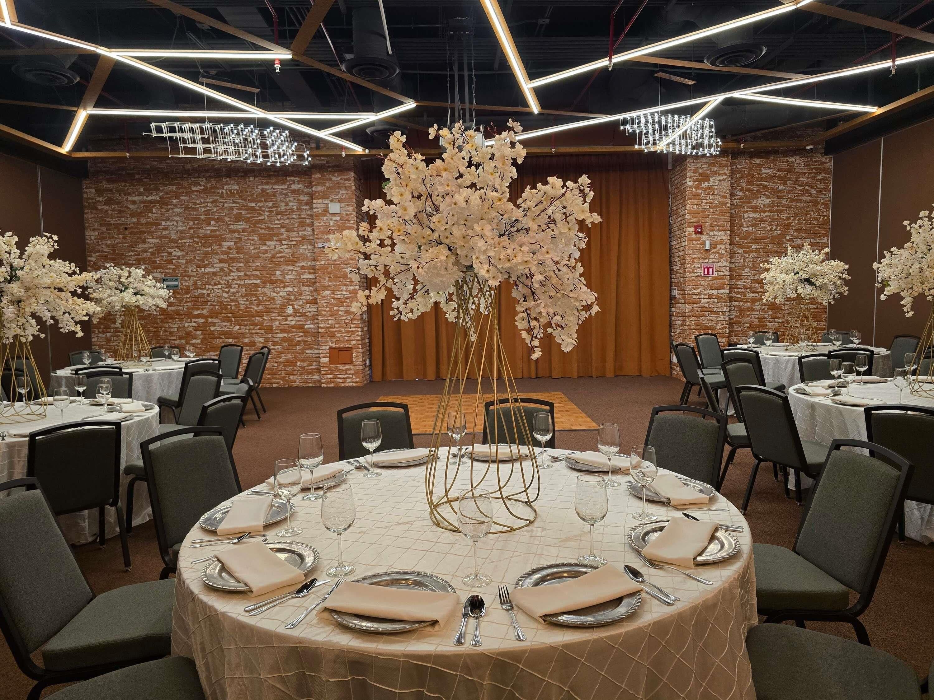 A conference room with round tables, chairs, and a brick wall.
