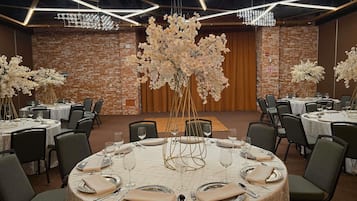 A conference room with round tables, chairs, and a brick wall.