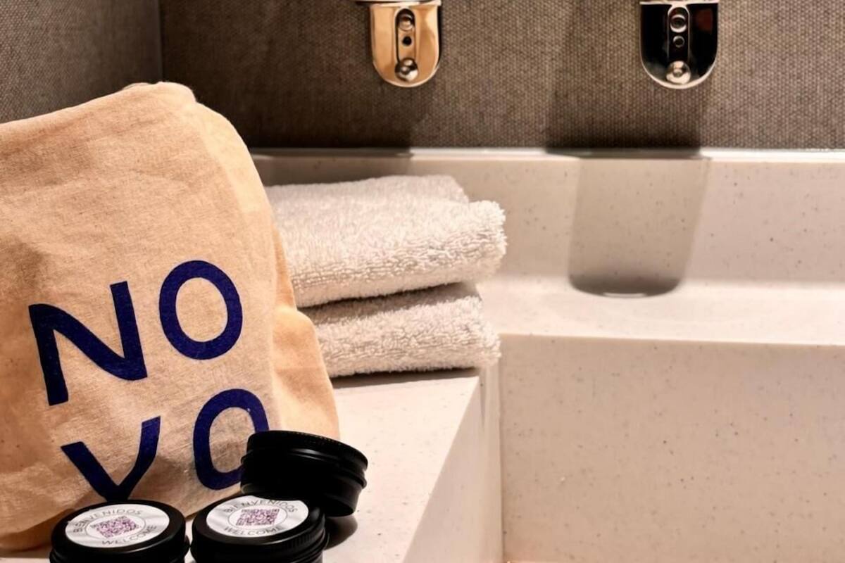 A bathroom with two bottles of hand and body lotion, a towel, and two small containers on the counter.