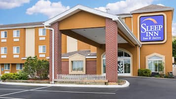 Un hotel Sleep Inn con fachada de ladrillo, un acceso cubierto y un estacionamiento.