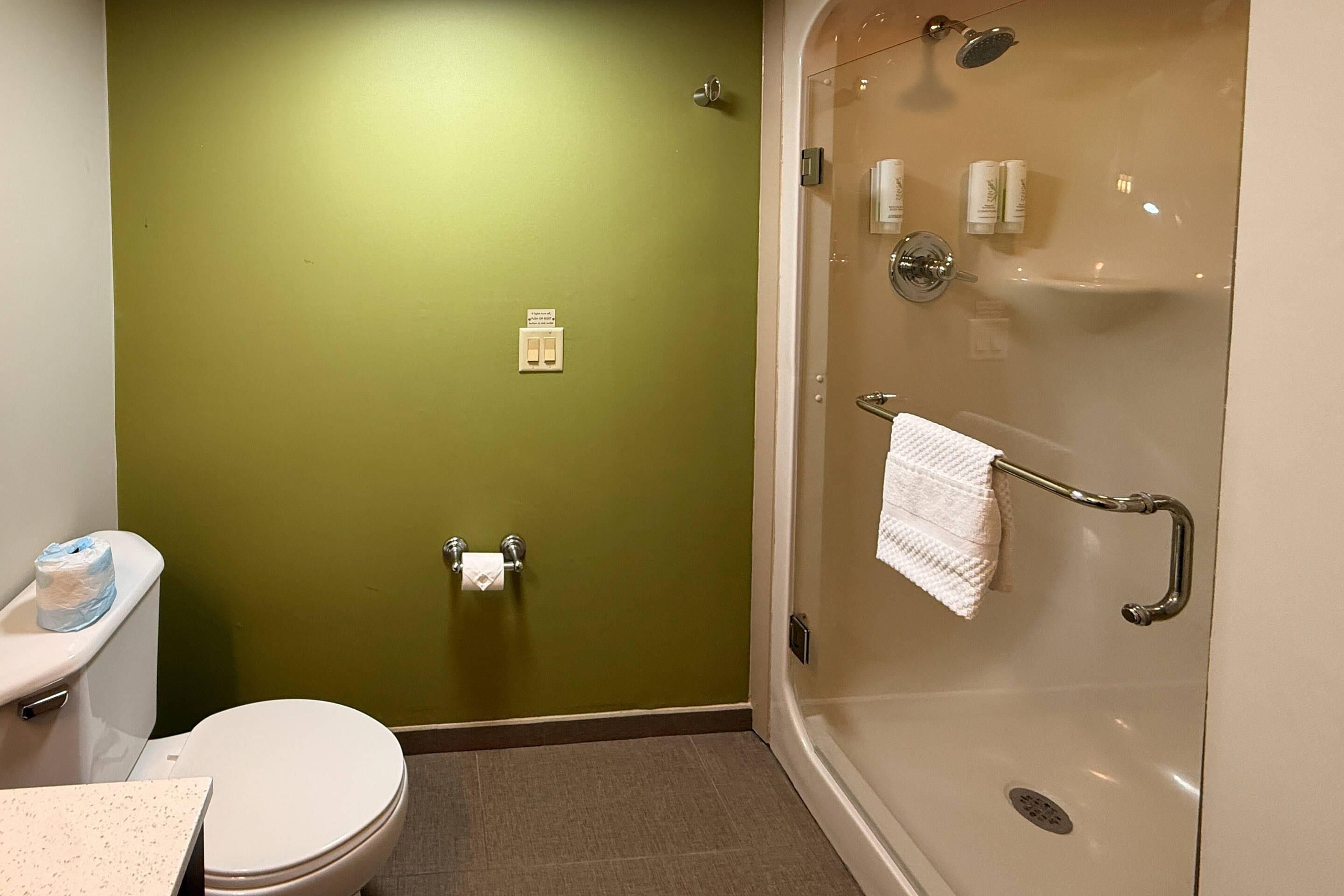 A bathroom with a toilet, a shower stall, and a towel rack.