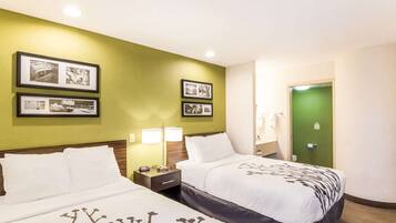 A hotel room with two beds, green walls, framed pictures, and a green door.