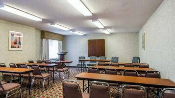 A conference room with tables and chairs, a large cabinet, and a patterned carpet.