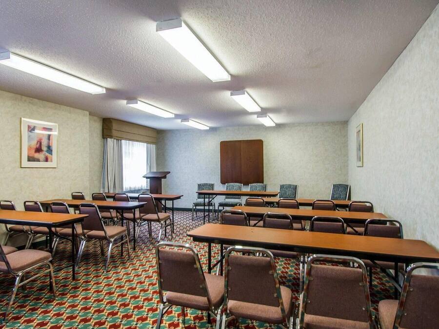 A conference room with tables and chairs, a large cabinet, and a patterned carpet.