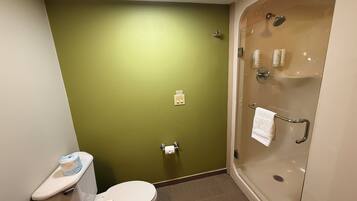 A bathroom with a toilet, a shower, and a green wall.